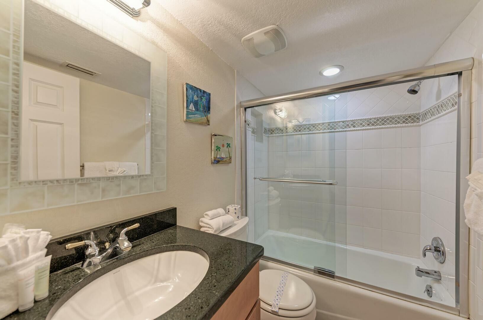 A bathroom with a large sink, mirror, and glass-enclosed shower.