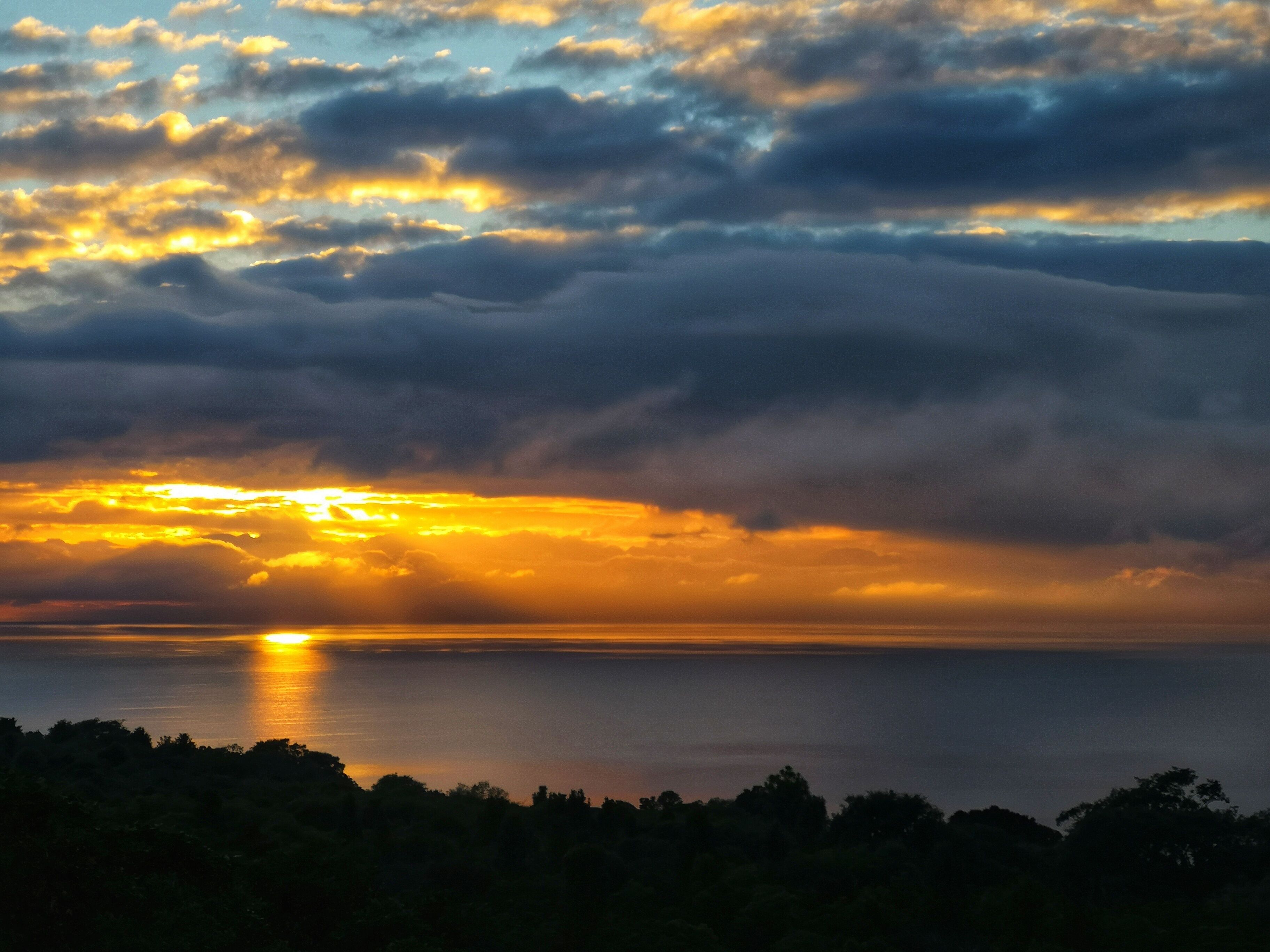 Een zonsondergang boven een wateroppervlak met wolken.