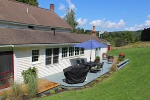Una casa con patio cubierto, muebles de exterior y una antena parabólica.