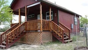 A red wooden house with a wooden staircase leading to a porch. - Welcome to Bandera Stronghold - Red Cloud Cabin (Bandera)
