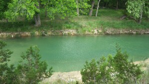A natural landscape with a body of water, trees, and grassy areas. - Welcome to Bandera Stronghold - Red Cloud Cabin (Bandera)