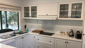 Une cuisine moderne avec des meubles blancs, un plan de travail noir et une fenêtre donnant sur un paysage verdoyant.