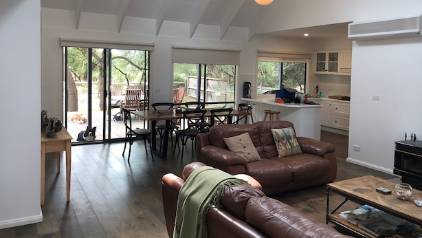 Un vaste espace de vie comprenant un canapé en cuir, une table basse en bois et une table à manger pour quatre personnes.