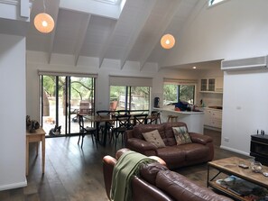 A spacious living area with a leather sofa, a wooden coffee table, and a dining table set for four. - Beachside  (Silverleaves)