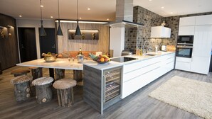 A modern kitchen with a central island, wooden stools, pendant lighting, and a built-in wine fridge. - B14 Luxury Penthouse down town for groups (Reykjavík)