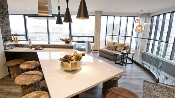 A modern kitchen with a large island, stools, and a view of the city through large windows. - B14 Luxury Penthouse down town for groups (Reykjavík)