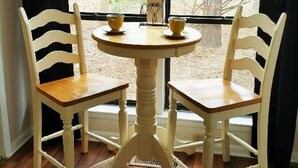 A round table with two chairs, each with a curved backrest, positioned in front of a window with a view of trees and a building. - 4 Bed/2 bath- sleeps 9, club cards avail, Golf cart, pets ok, neighborhood pool (St Helena Island)