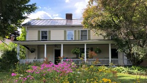 A two-story house with a covered porch and a garden in front. - Hyde Park Village Home near STOWE -- 4BR bedroom (Hyde Park)