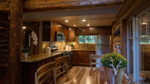 Cocina estilo cabaña de madera con encimeras de granito, armarios de madera y un ventanal grande.
