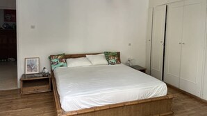 Un dormitorio con cama, mesita de noche, lámpara y armario.