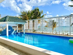 A swimming pool with a white fence and palm trees in the background. - PRIVATE BEACH HOUSE FOR BIG FAMILIES 7BR (Sleeps 20) Cancun, Punta Sam  (Cancún)