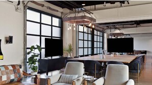 A modern office space with a large conference table, comfortable seating, and large windows. - Inn Cahoots on 6th: 15 BR/39 Beds, Pool, Roofdeck (Austin)
