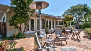 An outdoor patio with wooden furniture, a table, and a hanging light fixture. - CARMEL OASIS-Gorgeous Views 4 Bedroom 2.5- EXCEPTIONAL RATINGS (Carmel-By-The-Sea)