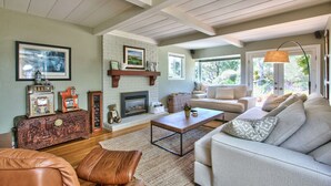A cozy living room with a fireplace, a sofa, a coffee table, and a leather armchair. - CARMEL OASIS-Gorgeous Views 4 Bedroom 2.5- EXCEPTIONAL RATINGS (Carmel-By-The-Sea)