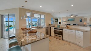 A spacious kitchen with a large island, modern appliances, and a view of the ocean.