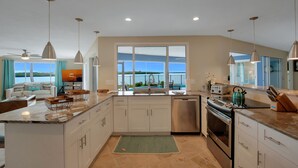 A modern kitchen with a large island, stainless steel appliances, and a view to the outside.