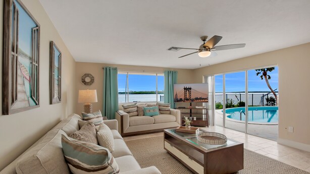 A spacious living room with a large sofa, a coffee table, and a view of a swimming pool.