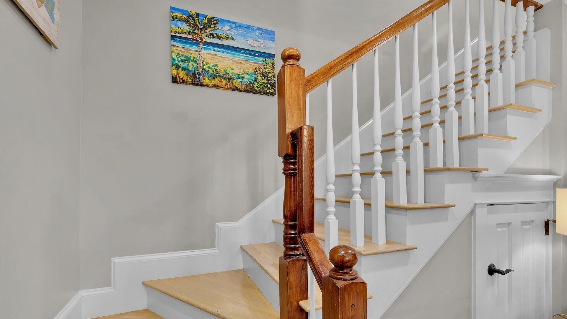 A staircase with wooden balusters and a handrail, leading to a landing with a door.