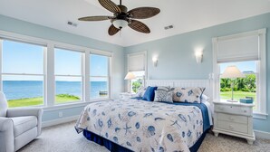 A bedroom with a large bed, a ceiling fan, and a view of the ocean. - Tramonti: Soundfront, Heated Pool, Golf (Nags Head)