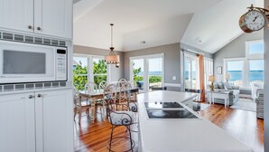 A spacious kitchen with a central island, white cabinetry, and a view of the outdoors. - Tramonti: Soundfront, Heated Pool, Golf (Nags Head)
