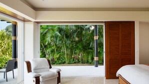 A bedroom with a bed, a white armchair, a wooden door, and a view of a lush garden. - Flat 701 Luxury Condo, Premier Golf Membership, Private Pool & Golf Cart (Punta Mita)