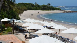 A beach with umbrellas, lounge chairs, and a sandy shore. - Flat 701 Luxury Condo, Premier Golf Membership, Private Pool & Golf Cart (Punta Mita)