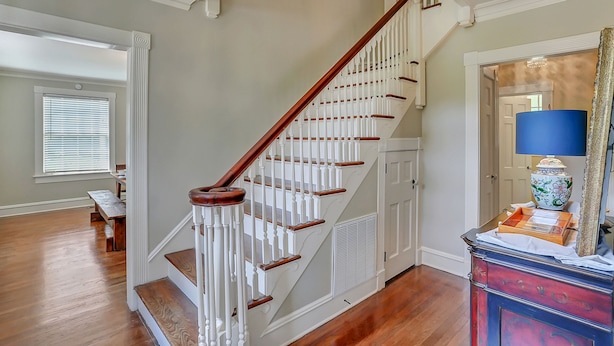 A staircase with white railings and wooden steps, leading to a landing with a bench and a lamp. - Huge Historic 4BR House w/  Patio, sleeps 12 (Jackson)