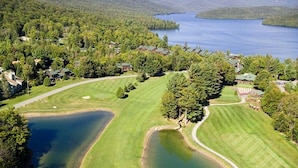 An aerial view of a golf course with multiple ponds, surrounded by dense forest and mountains. - Family Friendly Lake Placid Condo at Prestigious Whiteface Club-Resort-Sleeps 6 (Lake Placid)