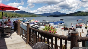 A lakeside dock with boats, a wooden deck, and a view of mountains. - Family Friendly Lake Placid Condo at Prestigious Whiteface Club-Resort-Sleeps 6 (Lake Placid)