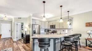 A modern kitchen with a large island, bar stools, and pendant lighting. - View for Miles! Remodeled Lands' End Luxury Condo - Wifi, Waterpark, Pool, Docks (Osage Beach)