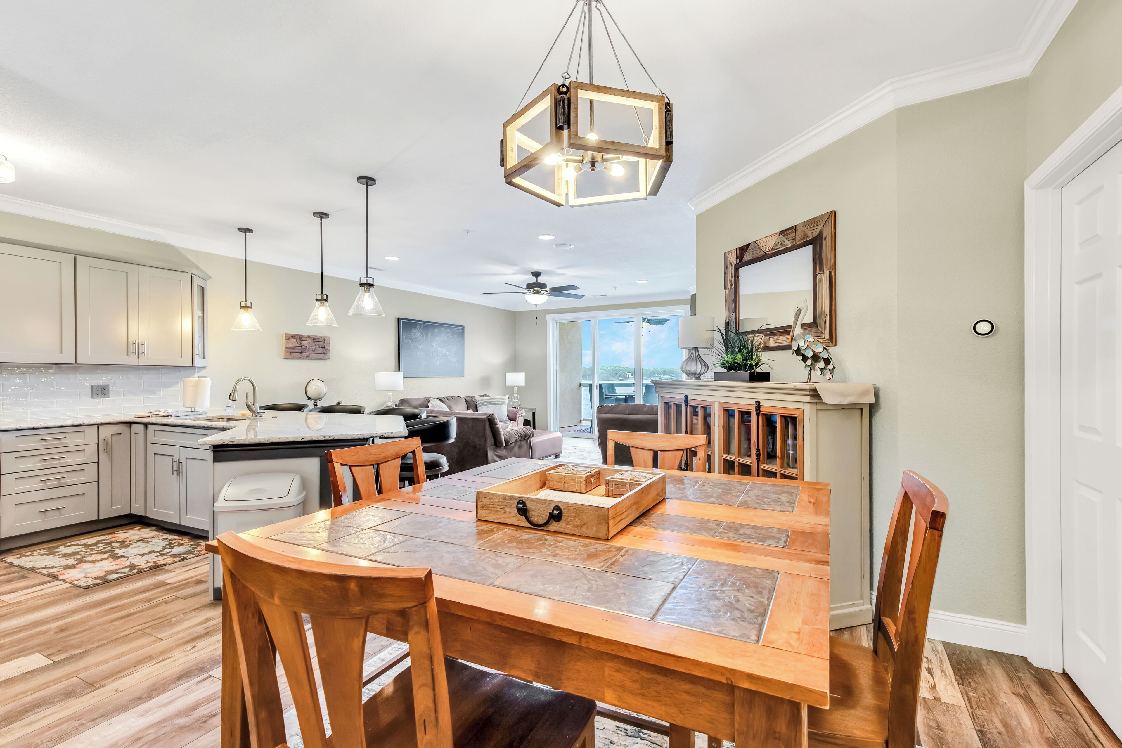 A spacious kitchen with wooden cabinets, a dining table with chairs, pendant lights, and a ceiling fan.