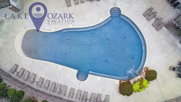 An aerial view of a swimming pool with lounge chairs and a sign for Lake Ozark Vacation Destinations.