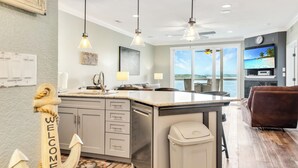 A modern kitchen with a large island, pendant lighting, and a view of the ocean. - View for Miles! Remodeled Lands' End Luxury Condo - Wifi, Waterpark, Pool, Docks (Osage Beach)