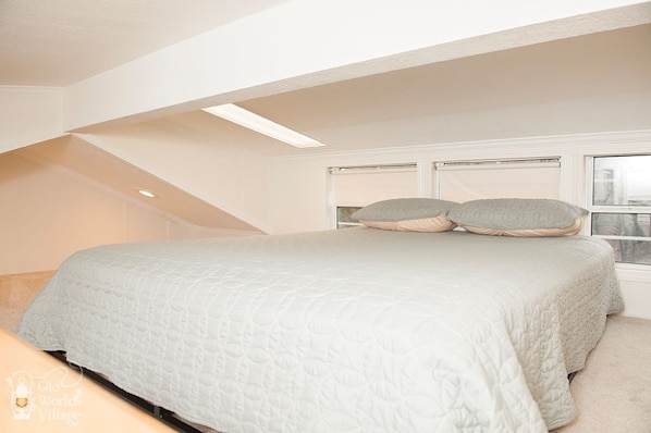 Een slaapkamer met een groot bed, een dakraam en een raam.