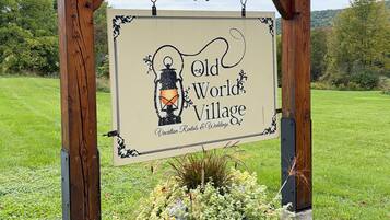 A wooden sign with a lantern and the text 'Old World Village' indicating a vacation rental and wedding venue.