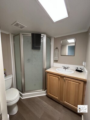 Baño con ducha, inodoro y tocador con lavabo.
