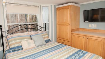 A bedroom with a bed, wooden wardrobe, and a television on the wall.