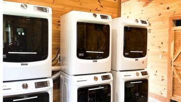 A stack of white appliances, including a dryer and a washing machine, in a wooden room with a wooden door.