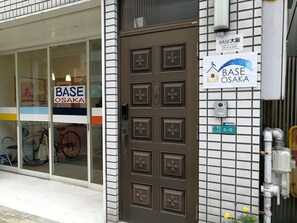 A building with a brown door and a sign reading "BASE OSAKA".