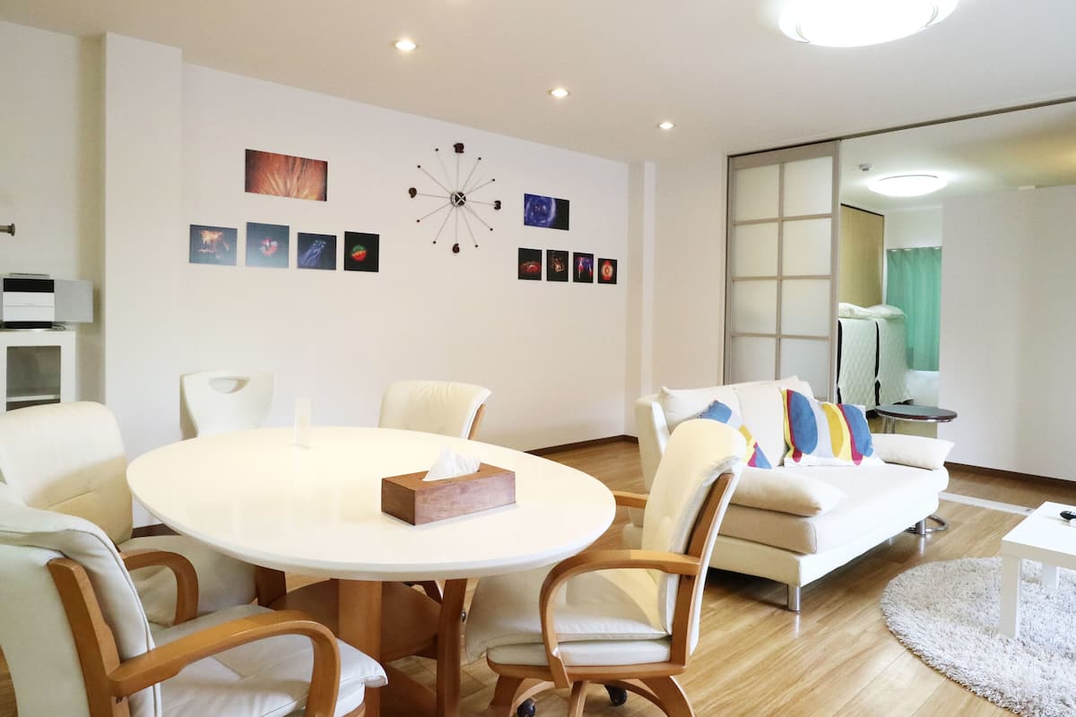 Una sala de estar moderna con una mesa de comedor redonda, sofás blancos y un gran reloj de pared.
