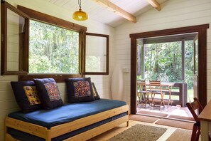 A cozy room with a wooden bed, large windows, and a view of the outdoors.