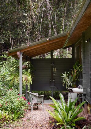 A covered outdoor area with a wooden bench, a small sink, and various plants.