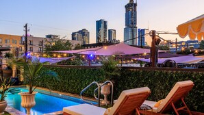 A rooftop pool area with lounge chairs and a view of the city skyline. - Inn Cahoots on 6th: 5BR/13Beds - Pool, Rooftop, Garden Bars, Walk to Everything (Austin)