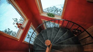 En spiraltrappa med en röd vägg och ett fönster med en växt i.