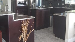 A modern kitchen with dark wood cabinets, stainless steel appliances, and a granite countertop. - Gunter's Paradise Retreat.   Pool paddle boards and kayaks! (Crystal River)