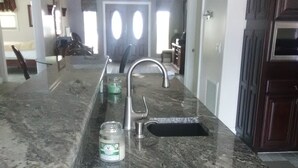 A kitchen with a granite countertop, stainless steel sink, and a ceiling fan. - Gunter's Paradise Retreat.   Pool paddle boards and kayaks! (Crystal River)