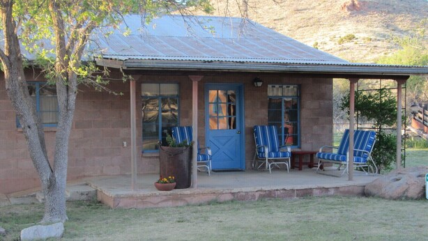 Un edificio rustico con un portico, una porta blu e un'area salotto all'aperto.