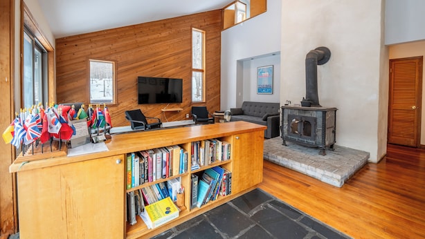 Un salon moderne avec un comptoir d’accueil en bois, des étagères, une cheminée et un téléviseur.