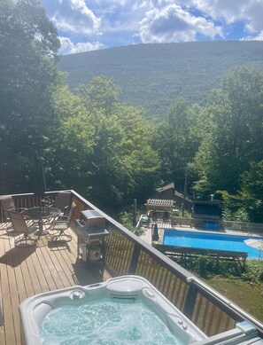 Eine Terrasse mit Whirlpool, Sitzgelegenheiten im Freien und einem Pool.