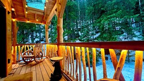 Une terrasse en bois avec une rambarde, une chaise berçante et une table.